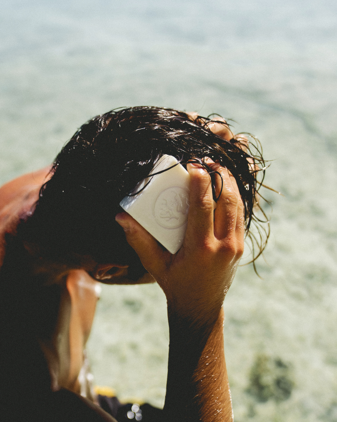 Young man using Wash Bloc Shampoo at the beach